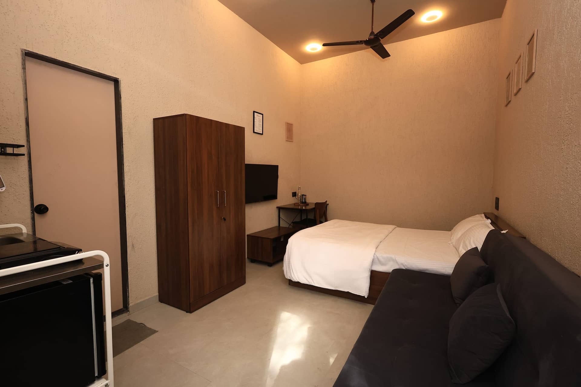 Bed, sofa, dark-wood wardrobe and wall-mounted TV in the studio