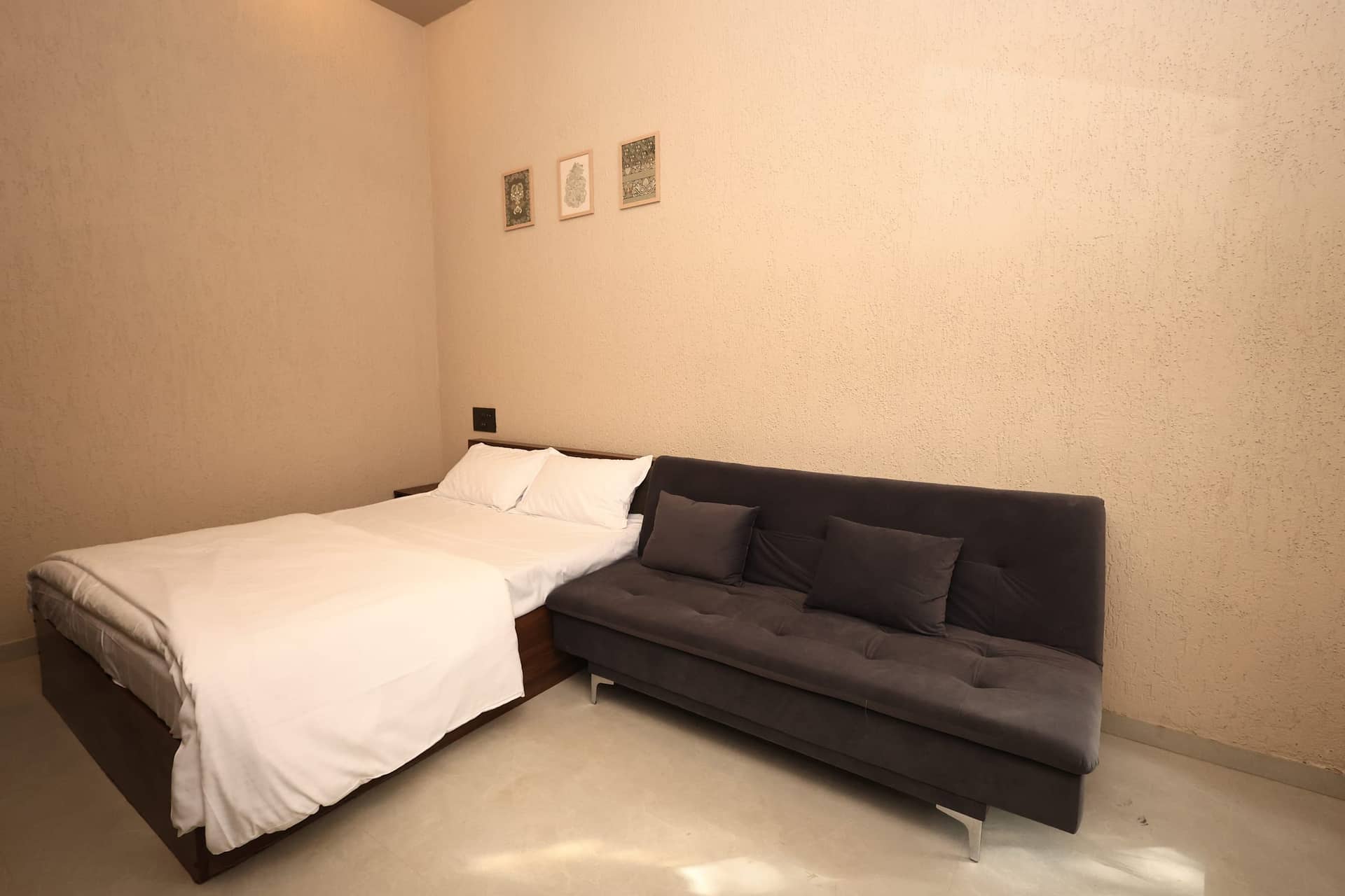 Double bed beside a grey sofa below framed prints