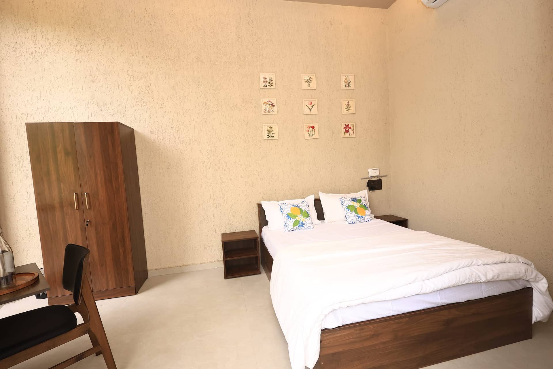 Raku bedroom with botanical prints and a dark-wood wardrobe