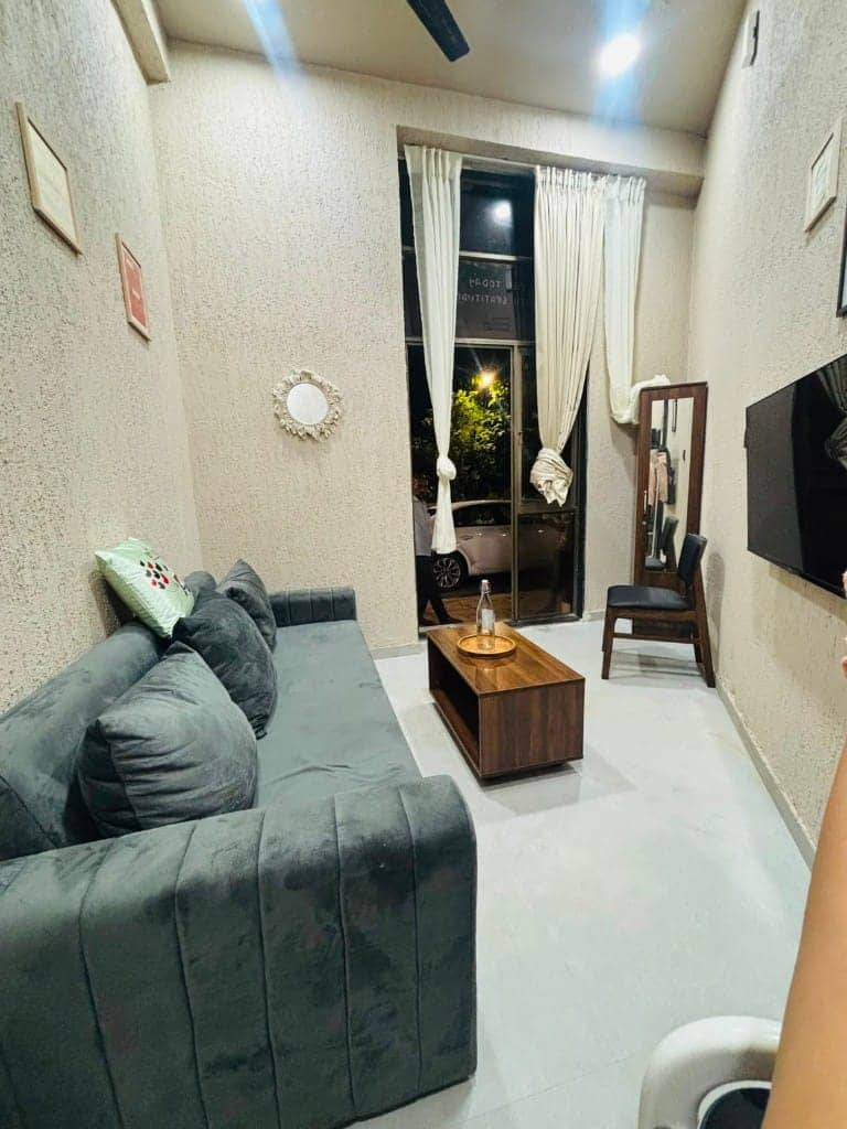 Yuzu's grey sofa lounge beside a curtained window and mirror