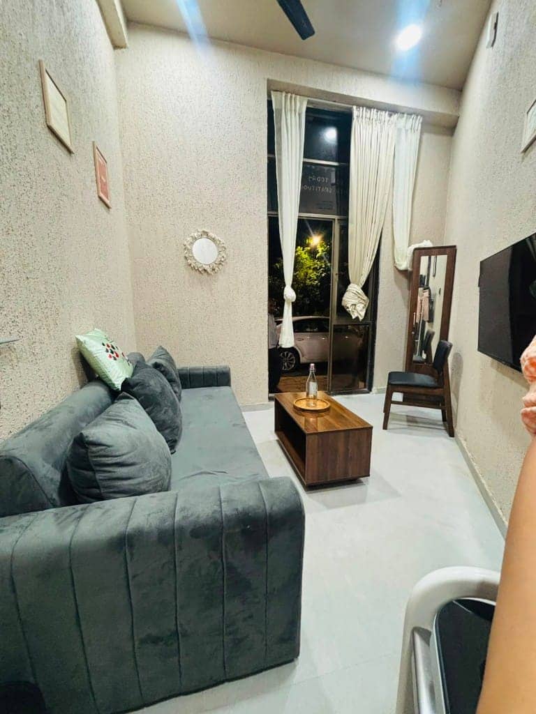 Angled view of Yuzu's sofa lounge, mirror and wall-mounted TV